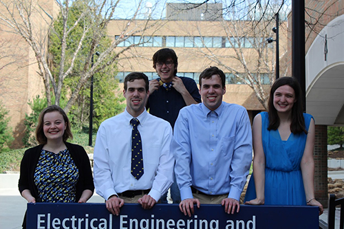 group of students around the EECS building sign